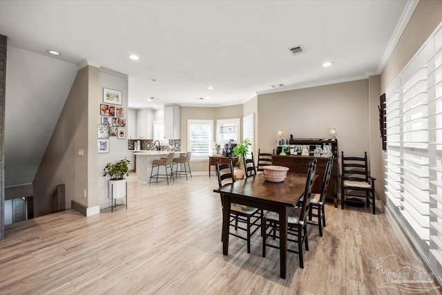 dining space with visible vents, light wood-style flooring, baseboards, and ornamental molding