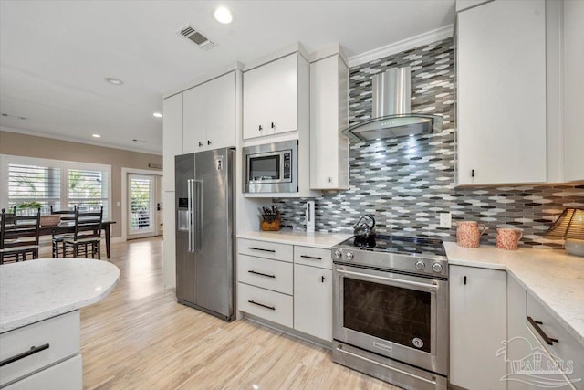 kitchen featuring crown molding, wall chimney range hood, visible vents, and stainless steel appliances