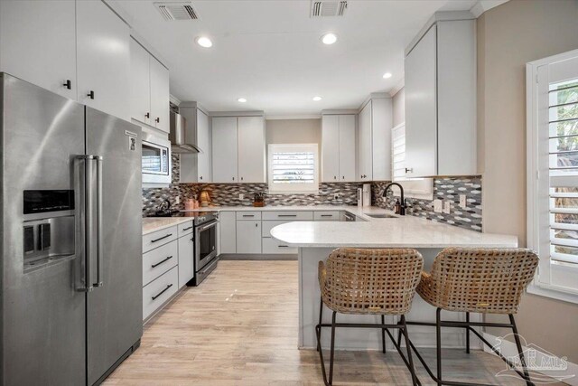 kitchen featuring a peninsula, visible vents, premium appliances, and a sink