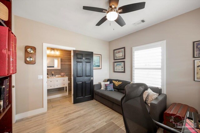 living room featuring visible vents, baseboards, light wood-type flooring, and a ceiling fan