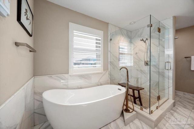 full bathroom featuring a wainscoted wall, a soaking tub, tile walls, and a stall shower