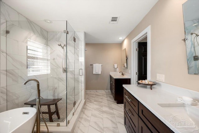 full bath featuring visible vents, a shower stall, two vanities, a freestanding tub, and a sink