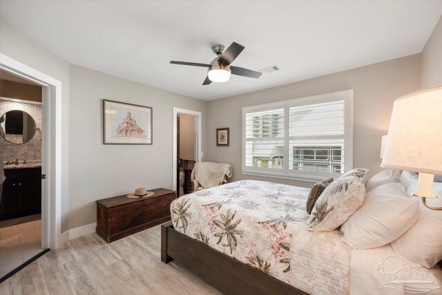 bedroom featuring baseboards, visible vents, light wood finished floors, ceiling fan, and a sink