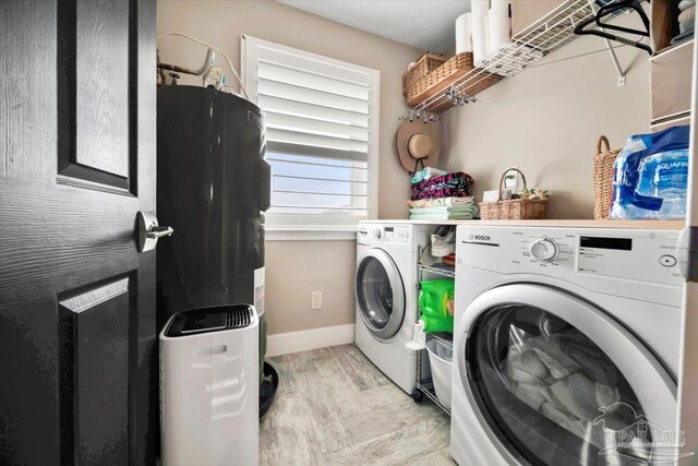 clothes washing area with laundry area, light wood-type flooring, baseboards, and washing machine and clothes dryer