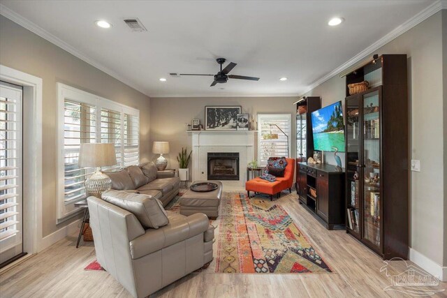 living area with visible vents, light wood finished floors, a fireplace, and crown molding