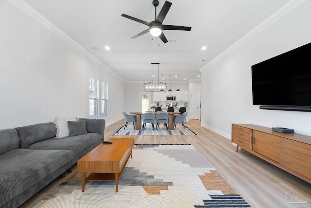 living room with ornamental molding, light wood-style flooring, and baseboards