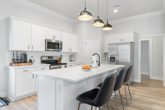 kitchen featuring tasteful backsplash, visible vents, appliances with stainless steel finishes, a kitchen bar, and white cabinetry