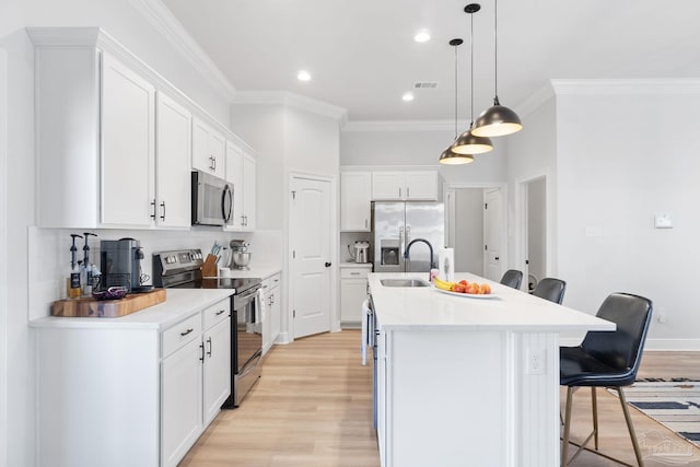 kitchen featuring backsplash, a kitchen island with sink, stainless steel appliances, a kitchen bar, and a sink