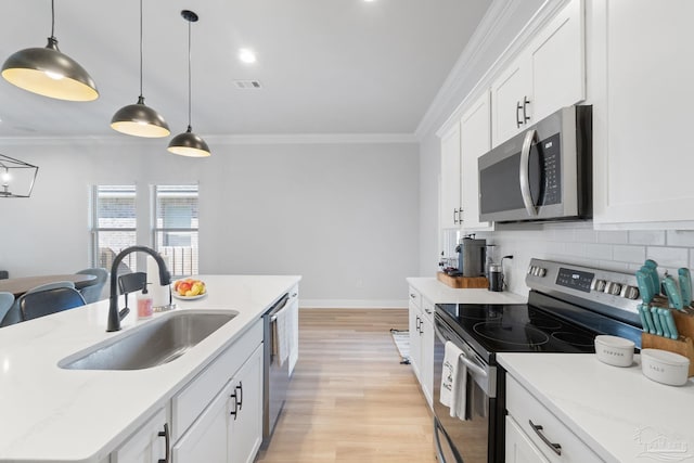 kitchen featuring stainless steel appliances, ornamental molding, a sink, and decorative backsplash