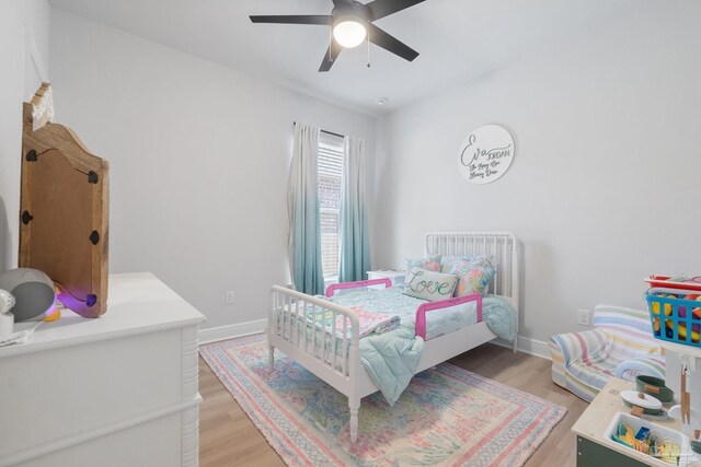 bedroom with light wood-style floors, baseboards, and a ceiling fan