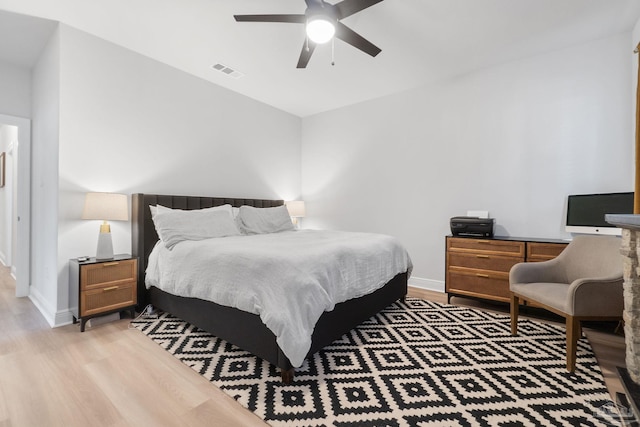 bedroom featuring a ceiling fan, baseboards, visible vents, and wood finished floors