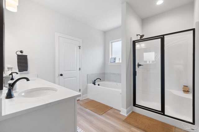 bathroom with a garden tub, a sink, a shower stall, and wood finished floors