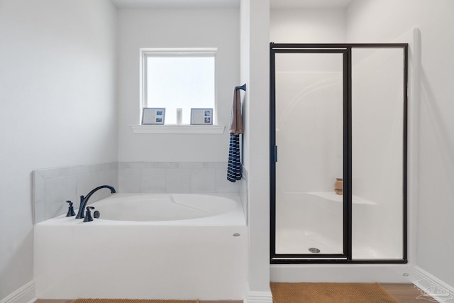 bathroom with a garden tub, a shower stall, and baseboards