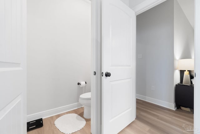 bathroom with toilet, baseboards, and wood finished floors