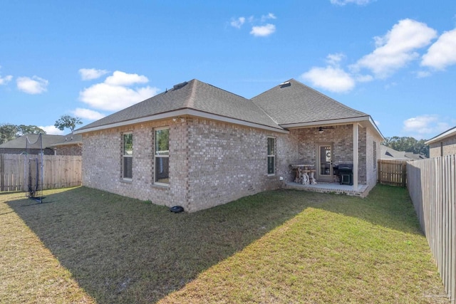 rear view of house with a patio, a fenced backyard, brick siding, a shingled roof, and a lawn