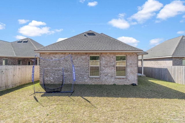 back of property featuring brick siding, a shingled roof, and a yard