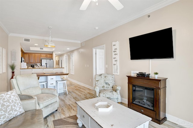401 E Beach Blvd Unit 1207, Gulf Shores, AL 36542 - living area featuring light wood-style flooring, ornamental molding, ceiling fan, baseboards, and a glass covered fireplace
