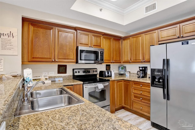 401 E Beach Blvd Unit 1207, Gulf Shores, AL 36542 - kitchen with appliances with stainless steel finishes, a sink, crown molding, brown cabinets, and light wood-style flooring