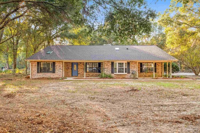 single story home featuring roof with shingles, a porch, and brick siding