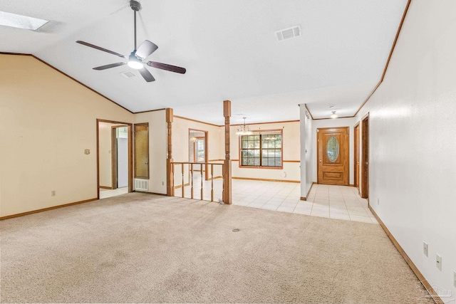 empty room featuring lofted ceiling with skylight, light colored carpet, and ceiling fan