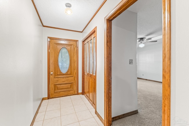 entryway with ceiling fan, light colored carpet, crown molding, and a textured ceiling