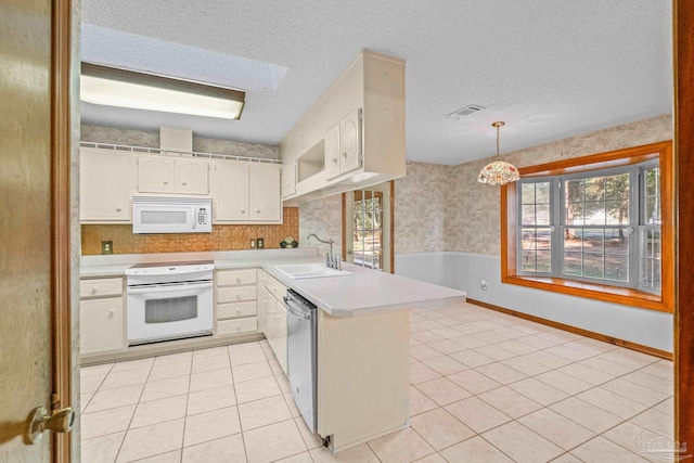 kitchen featuring sink, white appliances, white cabinetry, hanging light fixtures, and kitchen peninsula