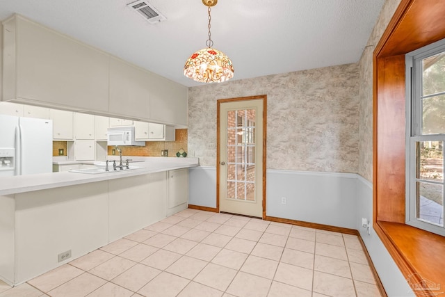 kitchen featuring sink, white appliances, light tile patterned floors, white cabinetry, and decorative light fixtures