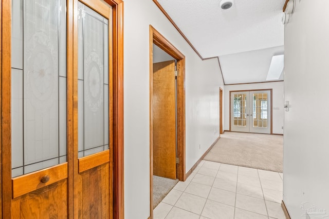 hallway featuring french doors, lofted ceiling, light carpet, and a textured ceiling