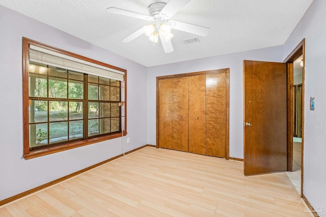 unfurnished bedroom with a textured ceiling, a closet, ceiling fan, and light wood-type flooring