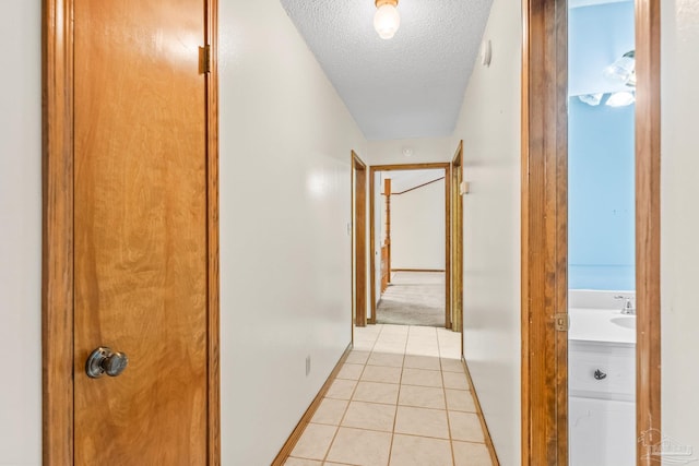 hallway with light tile patterned floors and a textured ceiling