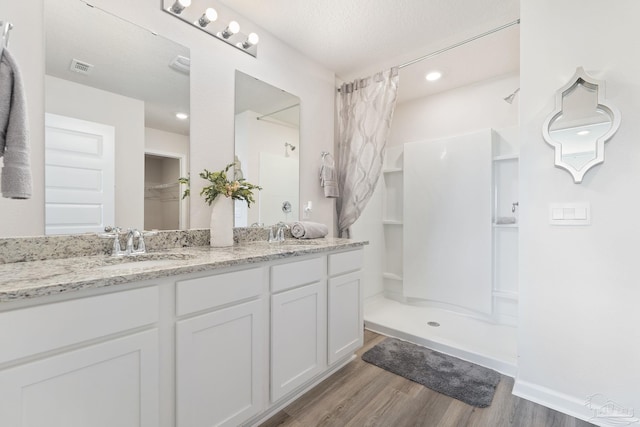 bathroom with hardwood / wood-style floors, vanity, a shower, and a textured ceiling