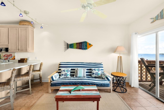 tiled living room featuring ceiling fan, a water view, and sink