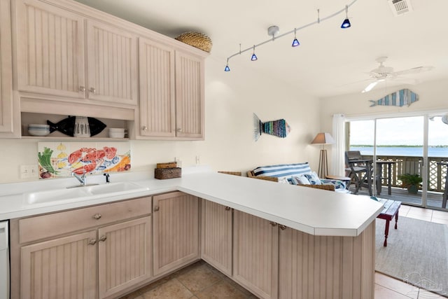 kitchen featuring a water view, light tile patterned floors, sink, white dishwasher, and kitchen peninsula