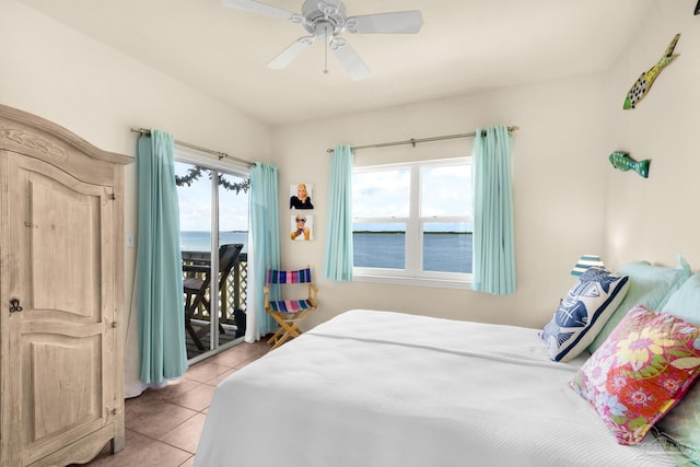 bedroom with multiple windows, access to exterior, a water view, and light tile patterned flooring