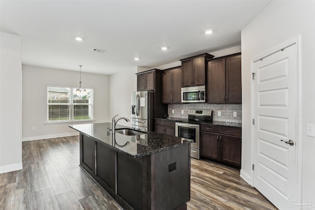 415 Broadleaf Cir, Cantonment, FL 32533 - kitchen with stainless steel appliances, a sink, dark brown cabinetry, a kitchen island with sink, and dark stone counters