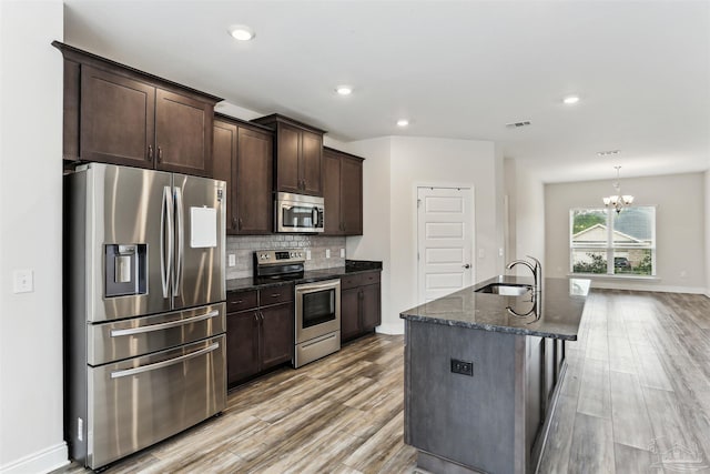 415 Broadleaf Cir, Cantonment, FL 32533 - kitchen featuring stainless steel appliances, a sink, baseboards, light wood-type flooring, and dark stone counters