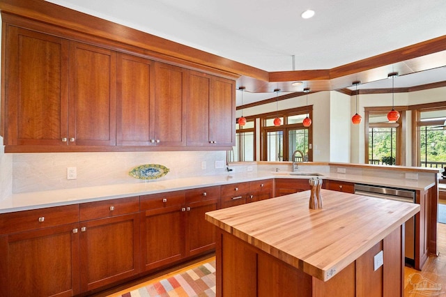 kitchen with a center island, sink, kitchen peninsula, hanging light fixtures, and light hardwood / wood-style flooring