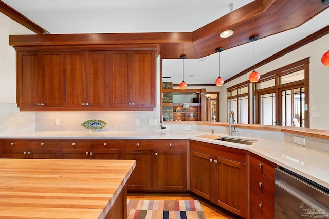 kitchen with tasteful backsplash, butcher block countertops, decorative light fixtures, stainless steel dishwasher, and ornamental molding