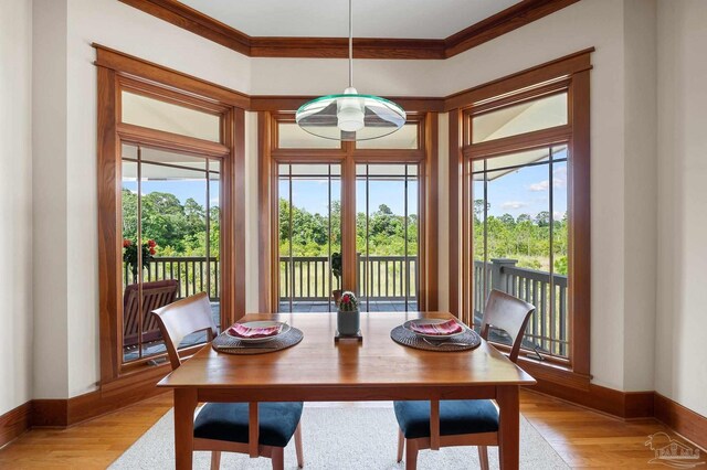 dining space with light wood-type flooring and crown molding