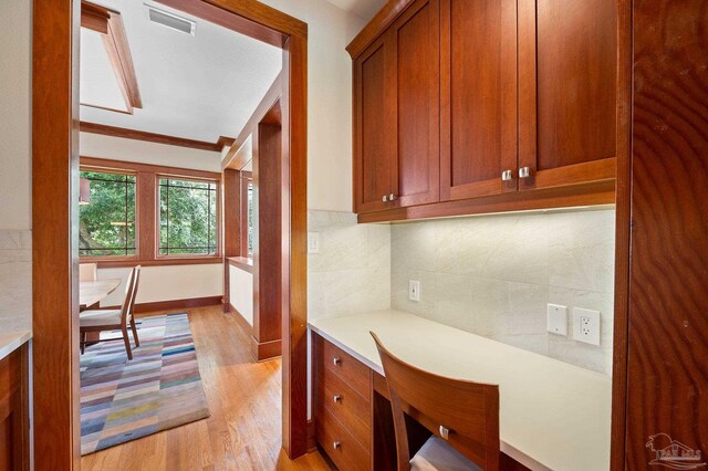 kitchen with light wood-type flooring, crown molding, and decorative backsplash