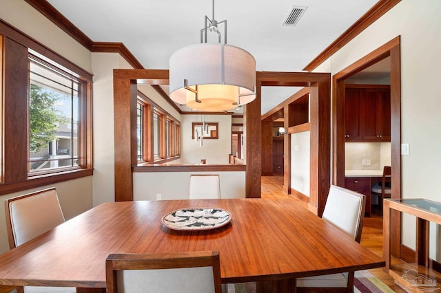 unfurnished dining area with light wood-type flooring and crown molding