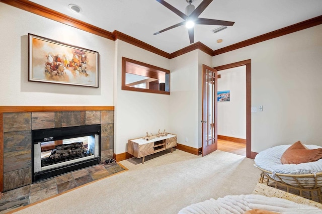 living room with carpet flooring, ceiling fan, a fireplace, and crown molding