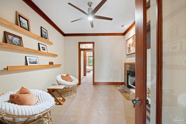 sitting room featuring carpet, crown molding, a tiled fireplace, and ceiling fan