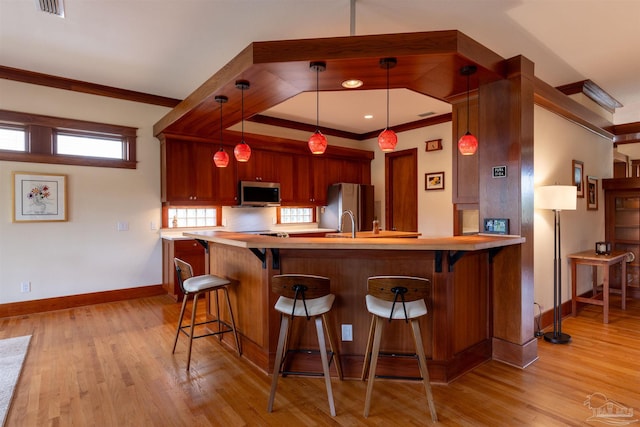 kitchen with kitchen peninsula, stainless steel appliances, crown molding, light hardwood / wood-style flooring, and decorative light fixtures