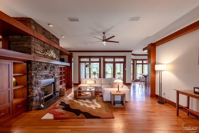 living room with ceiling fan, light hardwood / wood-style floors, a fireplace, and crown molding