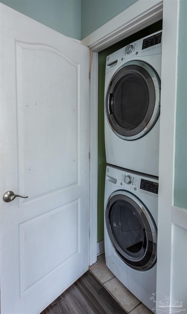 laundry room with dark wood-type flooring and stacked washing maching and dryer