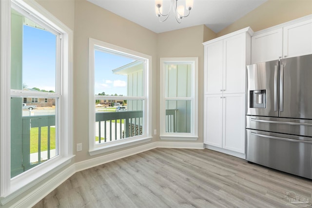 kitchen with stainless steel refrigerator with ice dispenser, light hardwood / wood-style flooring, an inviting chandelier, and white cabinets