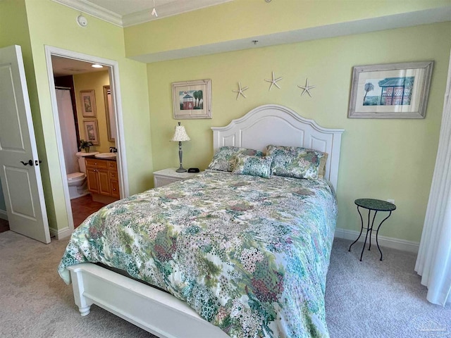 bedroom with ornamental molding, connected bathroom, and light colored carpet