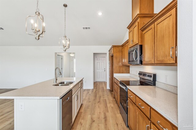 kitchen with sink, appliances with stainless steel finishes, hanging light fixtures, light hardwood / wood-style floors, and a center island with sink