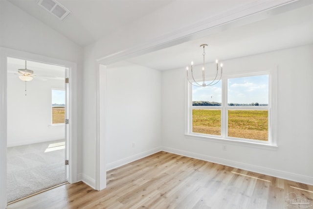 unfurnished dining area featuring lofted ceiling, ceiling fan with notable chandelier, and light hardwood / wood-style floors